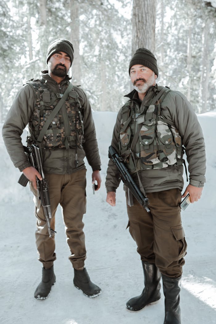 Home Two soldiers in winter uniforms stand armed in a snowy forest.